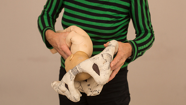 Hebamme mit Beckenmodell und Babypuppe